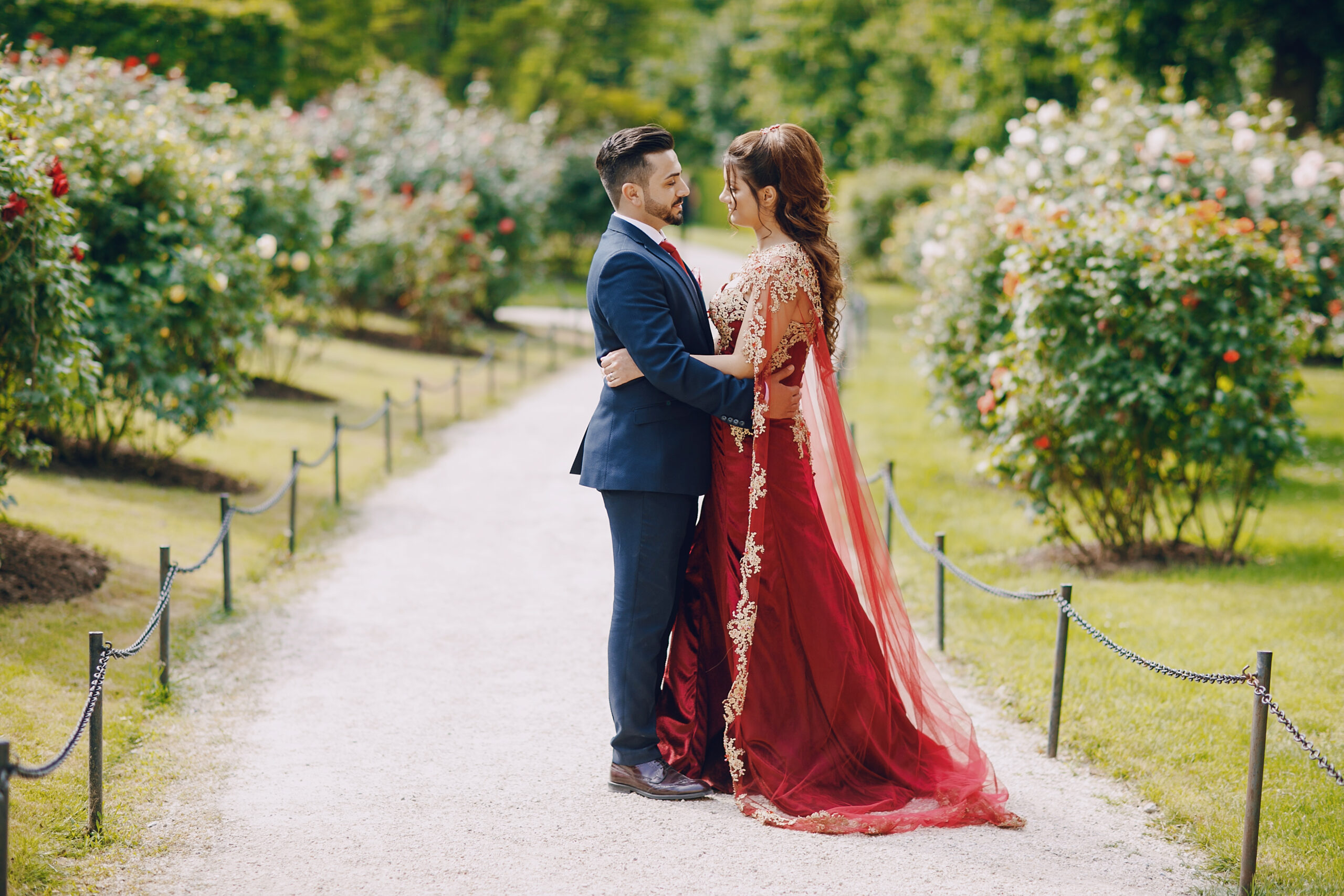 Beautiful woman in a long red dress walks around the city with her husband in a blue suit and with a beard